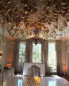 a room filled with lots of shiny balloons hanging from the ceiling and chandelier