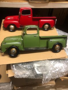 two red and green toy trucks sitting on top of cardboard