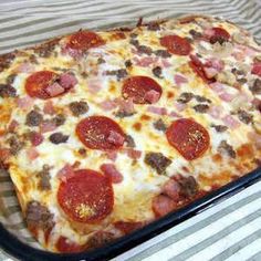 a square pizza with pepperoni, sausage and cheese in a pan on a table