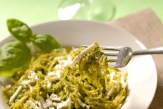 a white bowl filled with pasta and spinach