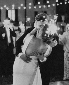 a man and woman kissing while holding sparklers