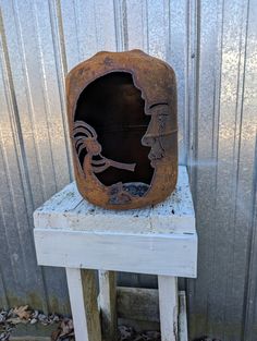 an old wooden box sitting on top of a white stool next to a metal wall