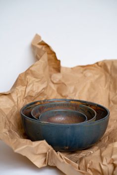 three blue bowls sitting on top of brown paper