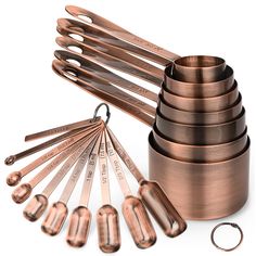 a stack of copper measuring spoons next to a set of six measuring spoons