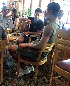 a group of men sitting around each other at a table with beers in front of them