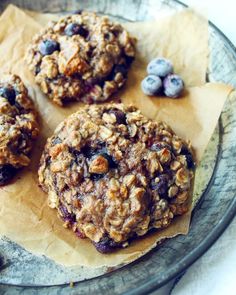 three blueberry oatmeal breakfast cookies on top of parchment paper with berries