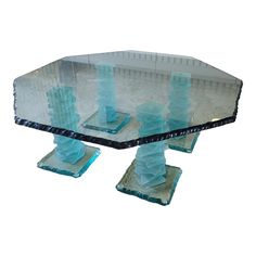 a glass table topped with blue candlesticks on top of a white floor covered in sand