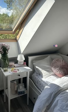 there is a small white bed in the corner of this room with a skylight above it