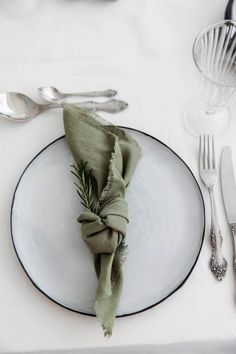 a white plate topped with a green napkin next to silverware and utensils