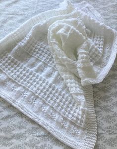 a white knitted blanket laying on top of a bed