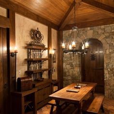 a wooden table sitting in front of a stone wall next to a doorway with wine glasses on it