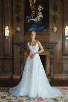 a woman standing in front of a fireplace wearing a wedding dress