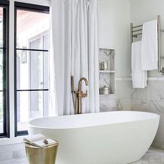 a white bath tub sitting in a bathroom next to a shower curtain and towel rack