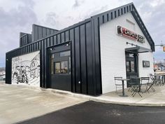 the outside of a restaurant with tables and chairs on the sidewalk near an empty parking lot