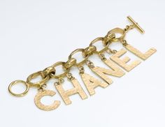 Chanel Letter Charm Bracelet Modern Jewelry With Gold-tone Logo Plaque As Gift, Designer Gold-tone Logo Bracelets As Gift, Modern Gift Jewelry With Gold-tone Logo Plaque, Designer Yellow Gold Jewelry With Logo Lettering, Vintage Gold Bracelet With Logo Charm, Chanel Letter, Luxury Vintage Charm Bracelet, Chanel Bracelet Silver, Formal Yellow Gold Jewelry With Gold-tone Logo Lettering