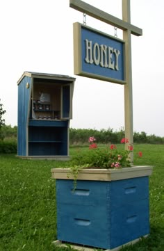 a blue beehive sitting in the grass next to a sign that says honey