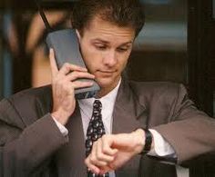 a man in a suit and tie is talking on a cell phone while looking at his watch