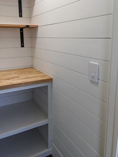 an empty shelf in the corner of a room with white walls and wood flooring