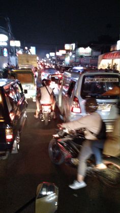 a busy city street filled with lots of cars and people riding bikes in the dark