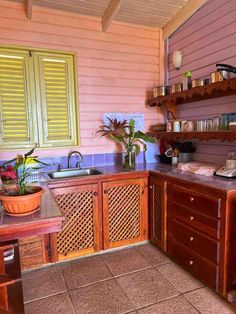 a kitchen with wooden cabinets and tile flooring next to a window filled with potted plants