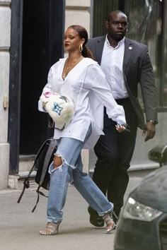 a man and woman walking down the street with one holding a soccer ball in his hand