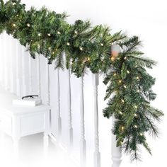 a christmas garland with lights hanging from it's sides next to a white piano