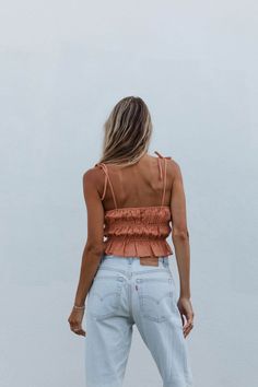 a woman standing in front of a white wall with her back turned to the camera