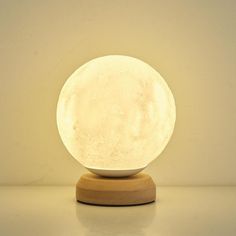 the moon lamp is sitting on top of a wooden stand with a white wall in the background