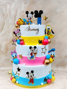 a three tiered cake with mickey mouse and other characters on it's sides