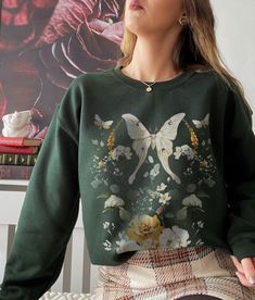 This is a Unisex-Style Fairycore Crewneck Sweatshirt. The soft, warm material is made from a blend of cotton and polyester. It has no itchy side seems and a trendy, loose fit. The cool design on this fairycore crewneck features a watercolor botanical and luna moth motif. PLEASE SIZE UP 1-2 SIZES FOR A TRENDY, LOOSE FIT! This design is an original, created by Jillian Anderson @ A Living Whimsy. She uses digital graphic design elements and collage and optimizes each image or illustration for a cri Crew Neck Cotton T-shirt In Fairycore Style, Spring Fairycore Crew Neck T-shirt, Fairy Grunge Crew Neck T-shirt With Screen Print, Spring Fairycore Graphic Print T-shirt, Crewneck Aesthetic, Fairycore Graphic Print Cotton T-shirt, Cottagecore Sweater, Aesthetic Crewneck, Cottagecore Clothes