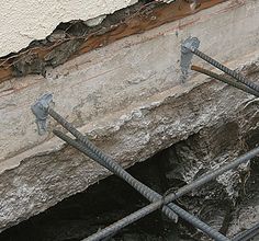 some wires are attached to the side of a concrete wall with holes in it that have been exposed