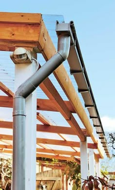 a metal pipe is attached to the side of a wooden structure with people in the background