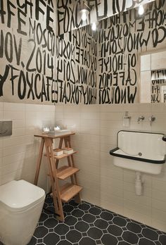 a white toilet sitting next to a sink in a bathroom under a large wall with letters on it