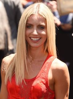 a woman with blonde hair is smiling and wearing a red top at an outdoor event