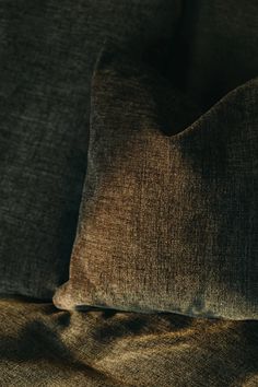 a brown pillow sitting on top of a bed next to a dark green blanket and pillows