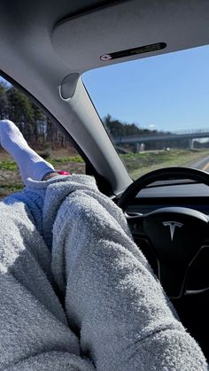 someone is sitting in the driver's seat of a car with their feet on the steering wheel