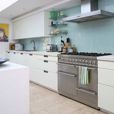 a stainless steel stove top oven sitting inside of a kitchen next to white cabinets and counter tops