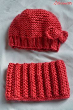 two crocheted hats and mittens are laying on a white sheet, one is red