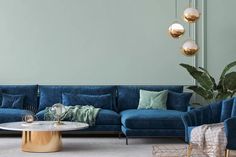 a living room with blue velvet couches and gold accents