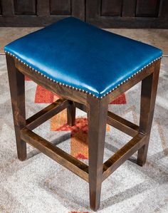 a blue leather stool sitting on top of a rug