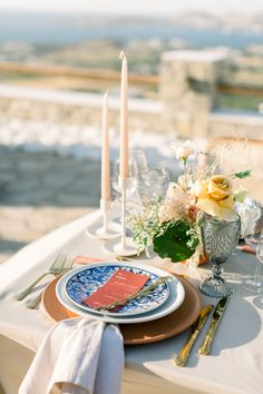 a table set with plates, candles and flowers