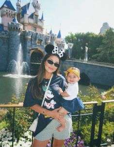 a woman holding a baby in front of a castle