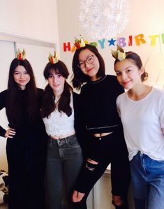 four young women standing next to each other in front of a birthday cake with candles on it