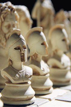 a chess board with several pieces of carved clay depicting people in armor and helmets on it