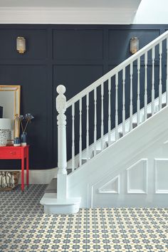 a room with blue walls and white railings next to a red table in front of a stair case