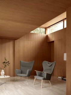 two chairs and a table in a room with wood paneling on the wall behind them