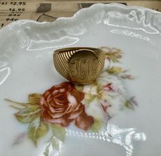 a gold ring sitting on top of a white plate with flowers and leaves around it