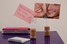 a couple's love note attached to two corks on a purple table top