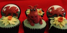 three cupcakes with dragon decorations on them