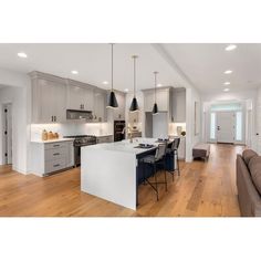 a large open concept kitchen and living room with hardwood floors, white walls and cabinets